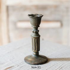 an old fashioned metal candle holder sitting on top of a table