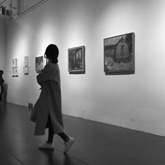 a woman is walking through an art gallery