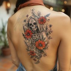 a woman with a tattoo on her back is looking down at the ground and flowers