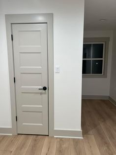 an empty room with white walls and wood floors