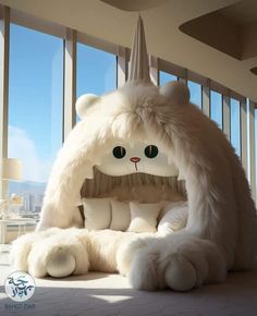 a large white stuffed animal sitting on top of a bed in a room next to tall windows