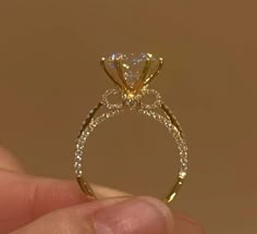 a close up of a person's hand holding a ring with a diamond on it