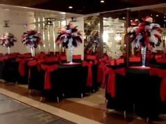 a room filled with black tables covered in red and white tablecloths next to a mirror