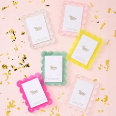 four different colored frames sitting on top of a pink surface with confetti around them