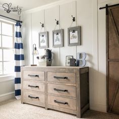 a dresser with drawers and pictures hanging on the wall in front of a striped curtain