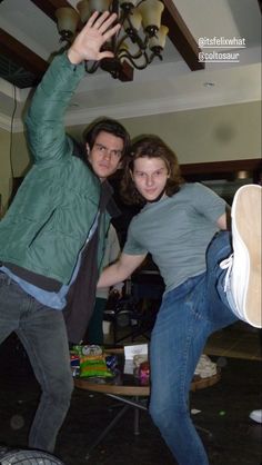 a man and woman are dancing in the living room with their shoes off to the side