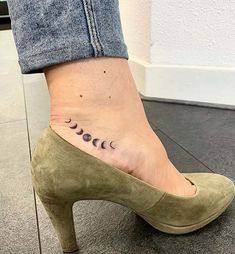 a woman's foot with three phases tattoo on her left ankle and the moon behind it