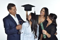 three women and one man are holding up graduation hats