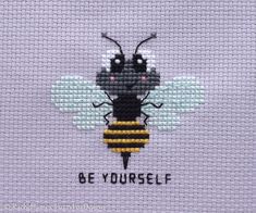 a cross stitch bee with the words be yourself written on it's back side