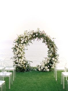 an outdoor ceremony set up with white flowers and greenery on the grass by the water