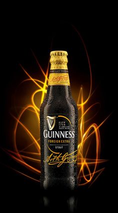 a bottle of guinness beer sitting on top of a black table next to an orange and yellow swirl