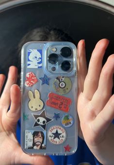 someone is holding up their phone case with some stickers on it and there are two hands in front of them