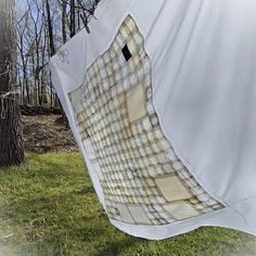 a white tarp hanging from a tree in the woods