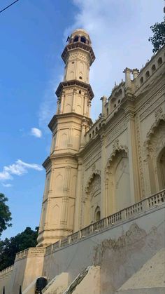 a tall tower with a clock on it's side next to stairs and trees