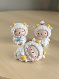 three little sheep figurines sitting on top of a wooden table