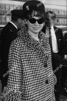 a woman in a hat and sunglasses standing next to another man wearing a suit and tie