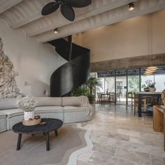 a living room filled with furniture next to a stone wall covered in black and white art