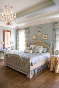 a bedroom with blue walls and wooden floors has a chandelier hanging from the ceiling