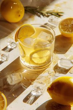 a glass filled with lemonade sitting on top of a table next to sliced lemons