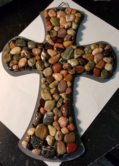 a cross made out of rocks sitting on top of a table