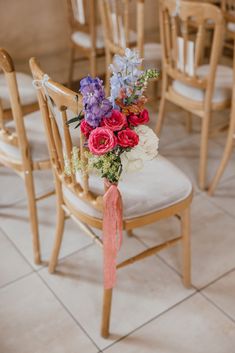 a bouquet of flowers sitting on top of a wooden chair in a room filled with chairs