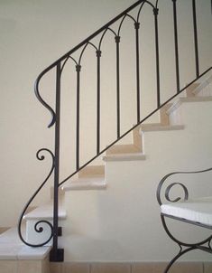 a set of stairs with wrought iron handrails next to a tiled floor and wall