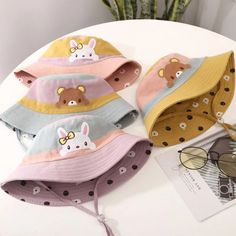 four hats with cartoon animals on them sitting on a white table next to a plant