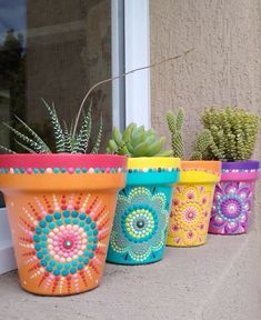 four colorful flower pots with succulents in them sitting on a window sill