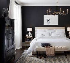 a bedroom with black walls, white bedding and a chandelier hanging above the bed