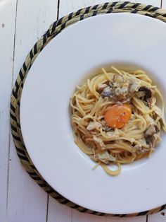 a white plate topped with pasta and an egg