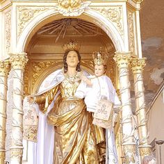 a statue of the virgin mary and child jesus in front of an ornate gold alter