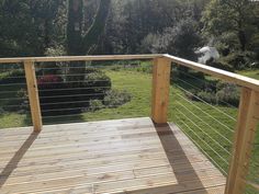 a wooden deck with metal railings in the grass