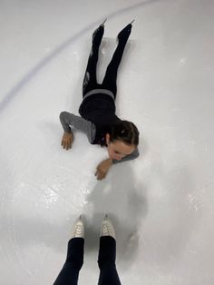 two people are skating on an ice rink and one is falling off his skateboard