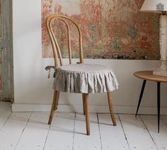 a chair with a ruffled seat sits in front of a painting on the wall