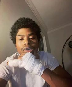 a young man brushing his teeth in the bathroom with white gloves on and one hand wrapped around his mouth