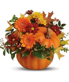 an orange pumpkin filled with flowers and leaves