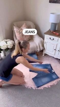 a woman kneeling down on the floor in front of a chair and looking at her jeans