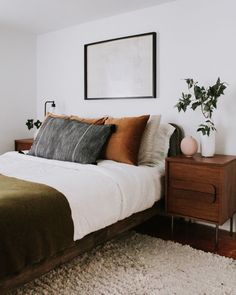 a bedroom with a bed, nightstands and plants on the side table in front of it