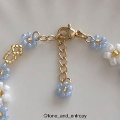 a close up of a bracelet on a white surface with gold chains and blue beads