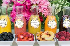 there are many different types of juices on the table with flowers in the background