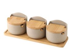 three pots with wooden lids sitting on a tray