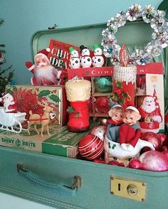 an open suitcase filled with christmas decorations and figurines on top of a table