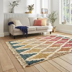 a living room with a white couch and colorful rugs on the wooden flooring