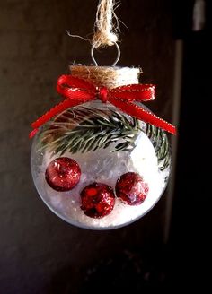 a snowman ornament hanging from a rope with red balls and pine needles