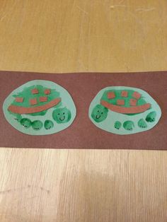 two paper plates with turtles on them are sitting on a brown tablecloth next to a wooden surface