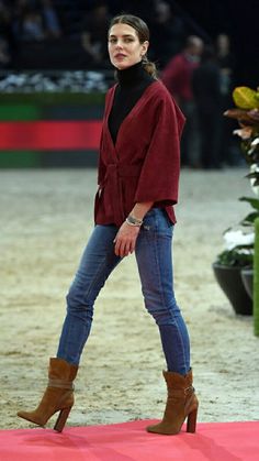 a woman walking across a red carpet on top of a pink floor covered in dirt