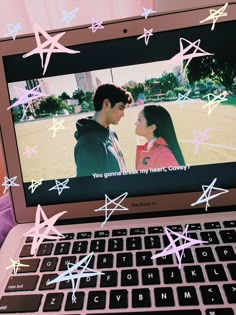 an open laptop computer sitting on top of a pink blanket covered in stars and confetti