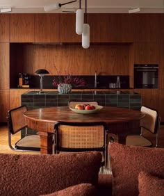 a wooden table sitting in the middle of a living room next to a kitchen area