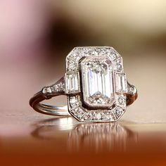 an emerald cut diamond ring sits on a table