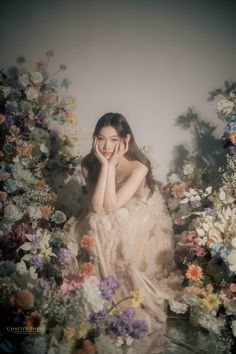 a woman sitting in front of flowers with her hand on her face